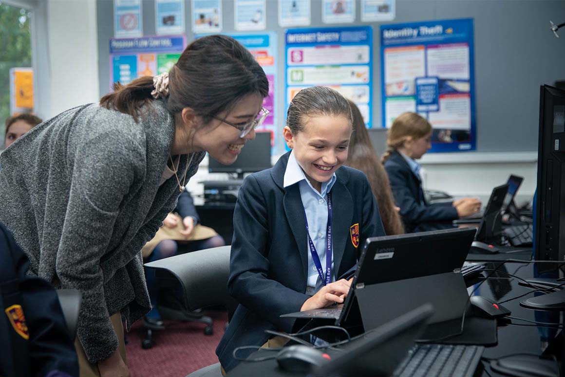 Young Kensington Park School student using a laptop with help from teacher